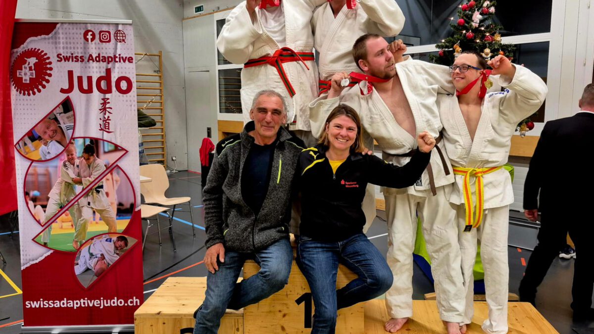 Vier ID-Judokas im Judoanzug mit Ihren zwei Coaches und den gewonnenen Medaillen auf dem Siegerpodest.